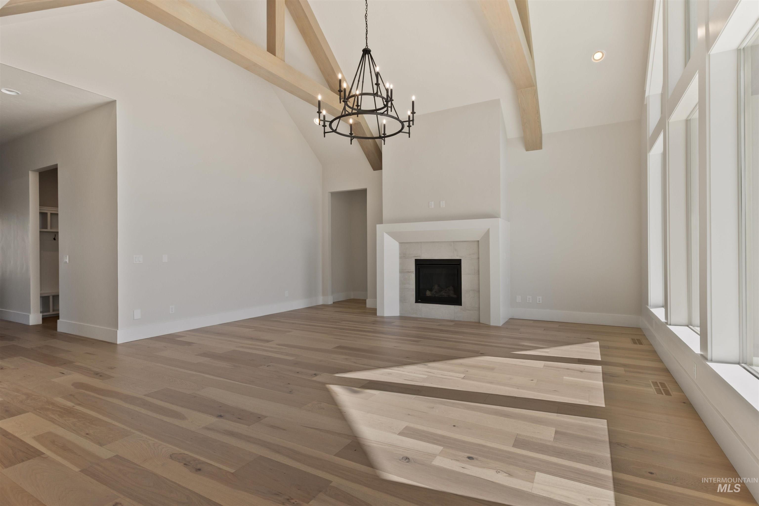 5857 South Highmark Avenue Meridian, ID 83642 - Photo 5 of 37 Unfurnished living room featuring high vaulted ceiling, beamed ceiling, light wood finished floors, a chandelier, and a fireplace