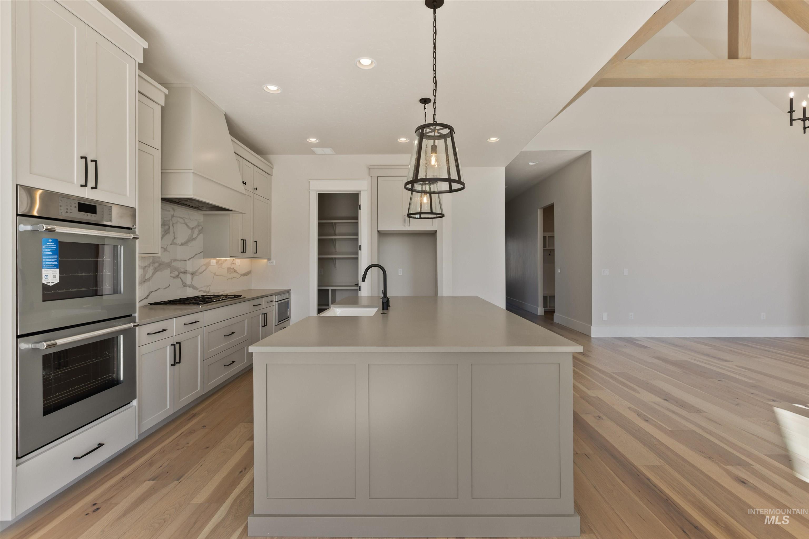 5857 South Highmark Avenue Meridian, ID 83642 - Photo 10 of 37 Kitchen with stainless steel appliances, recessed lighting, light wood-type flooring, tasteful backsplash, and custom exhaust hood