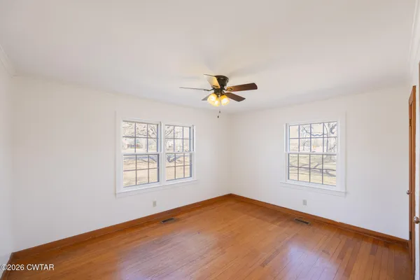 an empty room with windows and ceiling fan