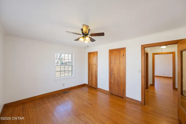 a view of an empty room with window and wooden floor