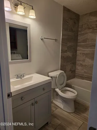 a bathroom with a granite countertop toilet a sink and mirror