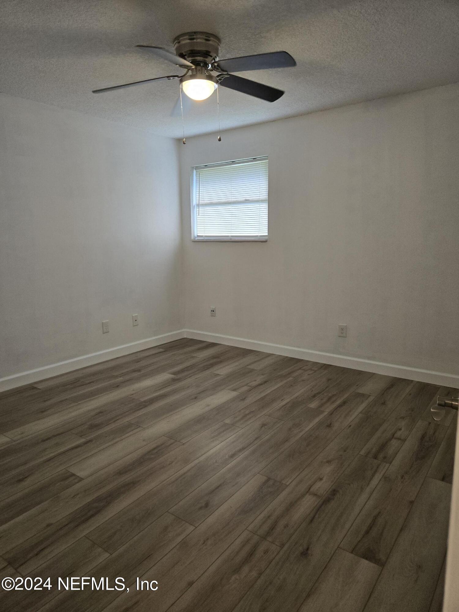1055 Stocks Street Atlantic Beach, FL 32233 - Photo 12 of 15 an empty room with wooden floor fan and windows
