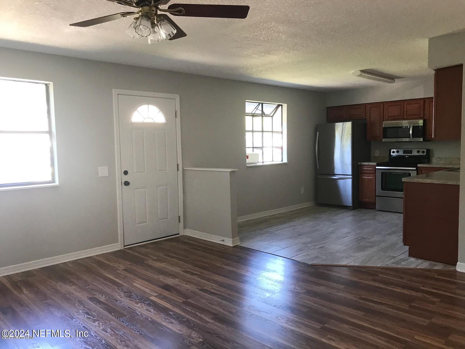1055 Stocks Street Atlantic Beach, FL 32233 - Photo 2 of 15 an empty room with wooden floor fan and windows