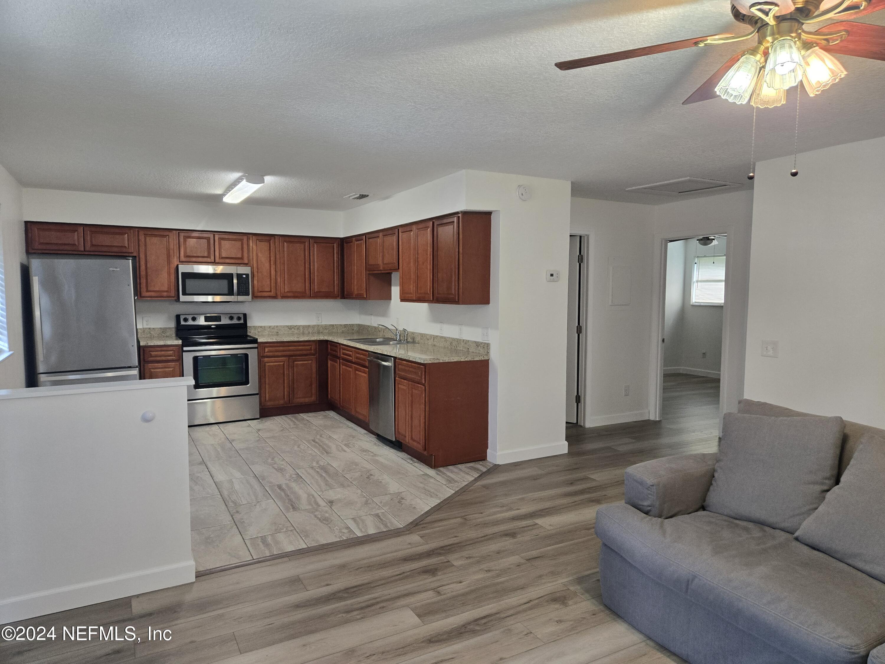 1055 Stocks Street Atlantic Beach, FL 32233 - Photo 4 of 15 a kitchen with stainless steel appliances granite countertop a stove top oven a sink dishwasher and a refrigerator with wooden floor
