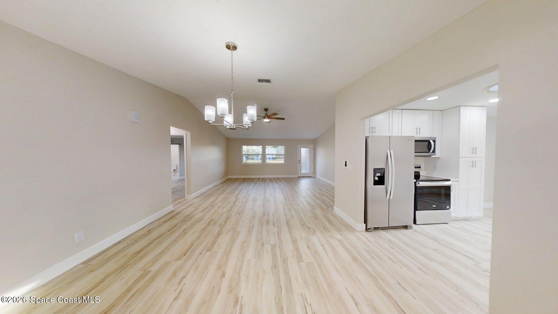 137 Concha Drive Sebastian, FL 32958 - Photo 12 of 29 a view of a room with wooden floor kitchen chandelier and stainless steel appliances