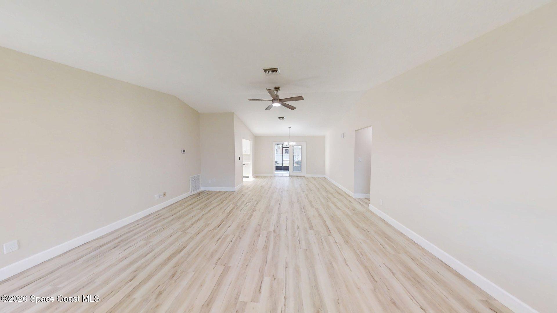 137 Concha Drive Sebastian, FL 32958 - Photo 6 of 29 a view of a big room with wooden floor a ceiling fan and entryway