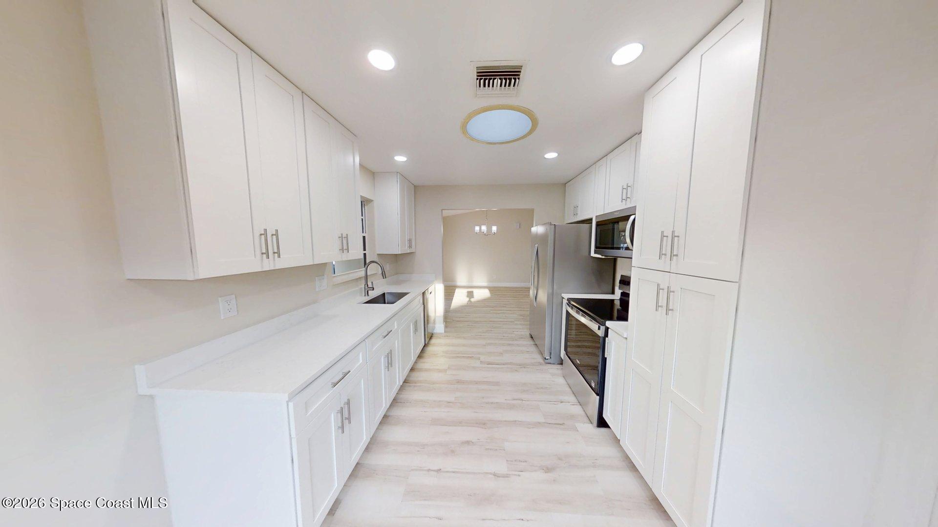 137 Concha Drive Sebastian, FL 32958 - Photo 9 of 29 a view of a kitchen with a sink and dishwasher a refrigerator with wooden floor