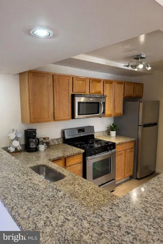 a kitchen with stainless steel appliances granite countertop a stove a sink a microwave and refrigerator