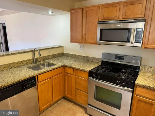 a kitchen with granite countertop stainless steel appliances a stove microwave and sink