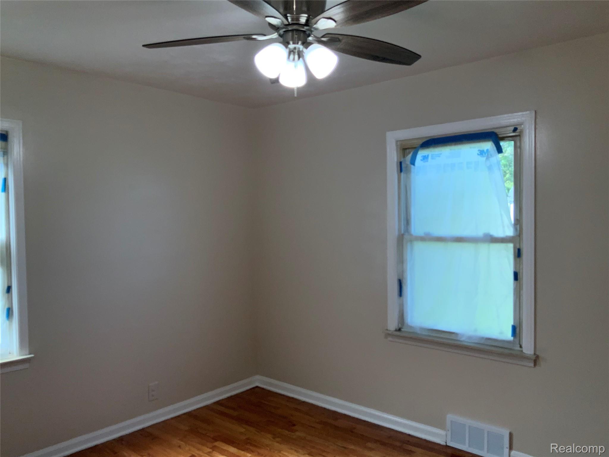 4034 Fleming Road Flint, MI 48504 - Photo 17 of 20 Hardwood flooring, painted walls, ceiling fan with integrated lighting, and white window trim