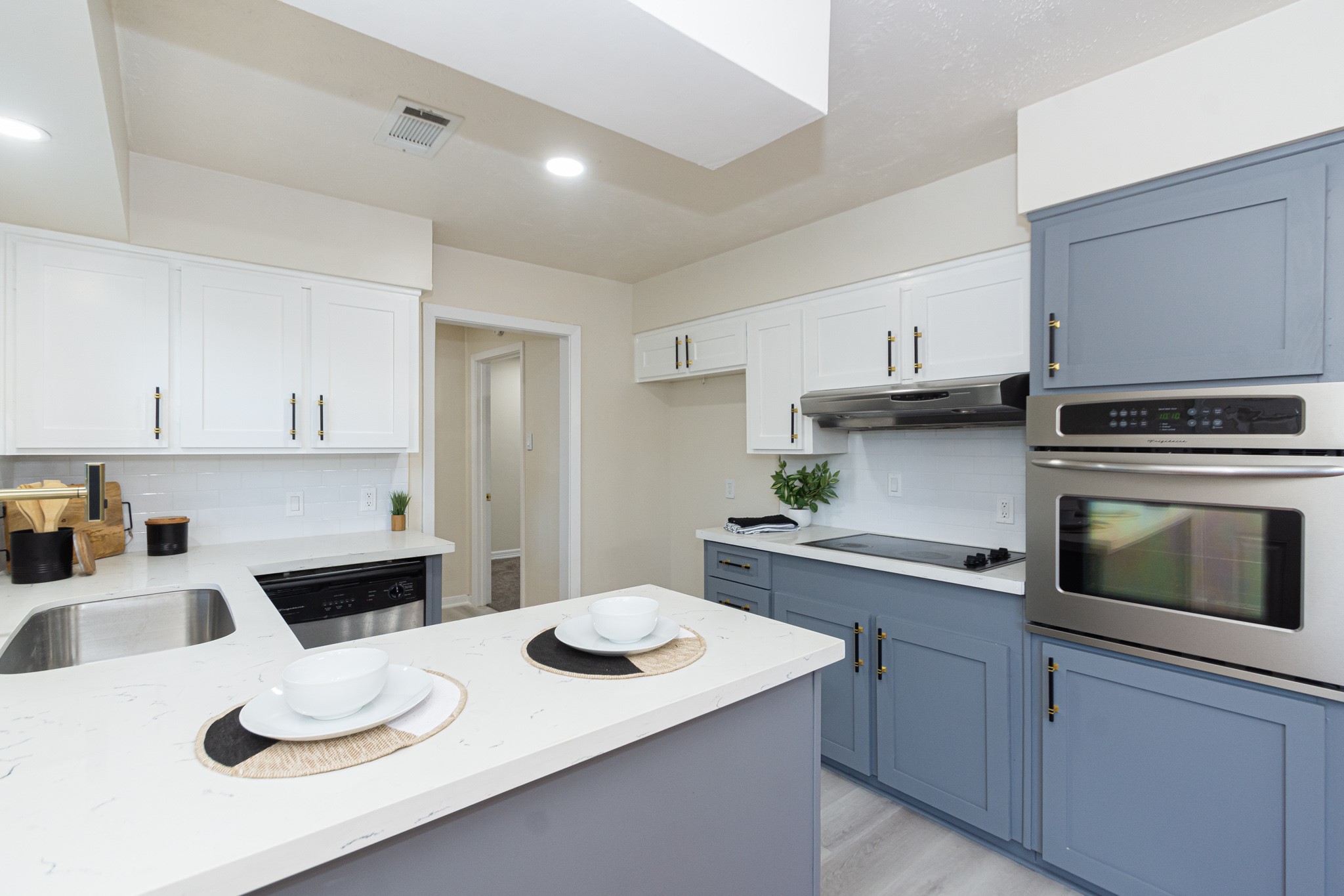 5834 Overdale Street Houston, TX 77033 - Photo 8 of 18 a kitchen with a sink dishwasher stove and white cabinets with wooden floor