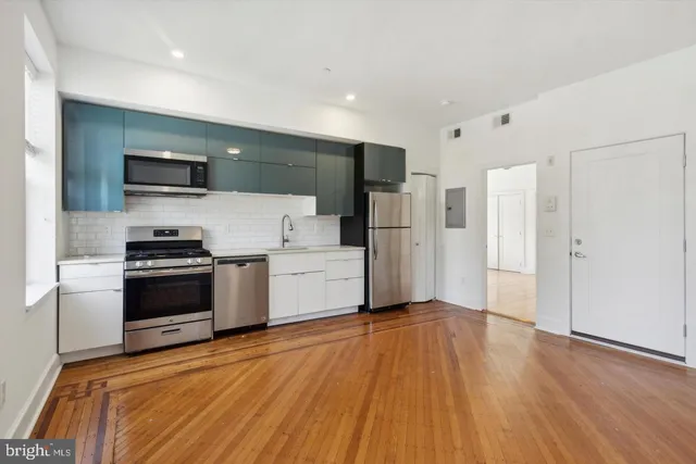 a kitchen with granite countertop a refrigerator and a stove top oven