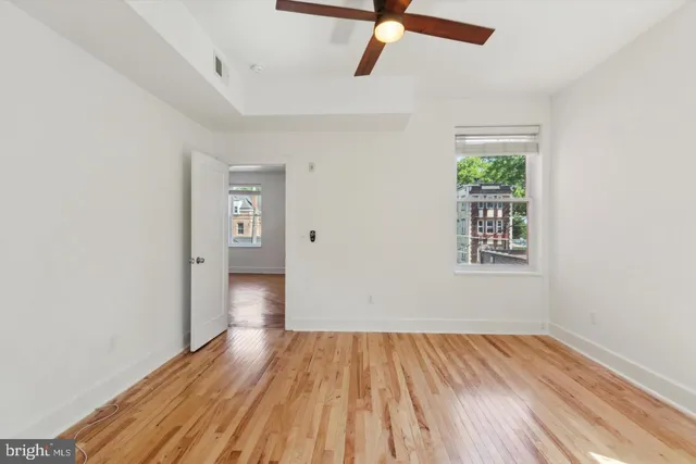an empty room with wooden floor cabinet and windows