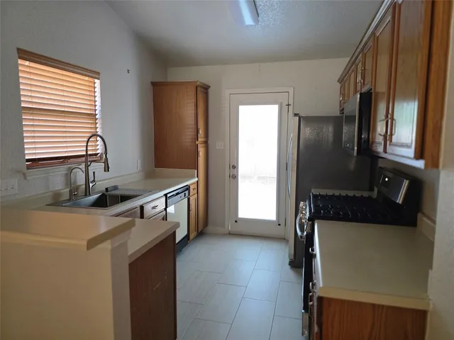 a kitchen with stainless steel appliances granite countertop a refrigerator a sink and a stove