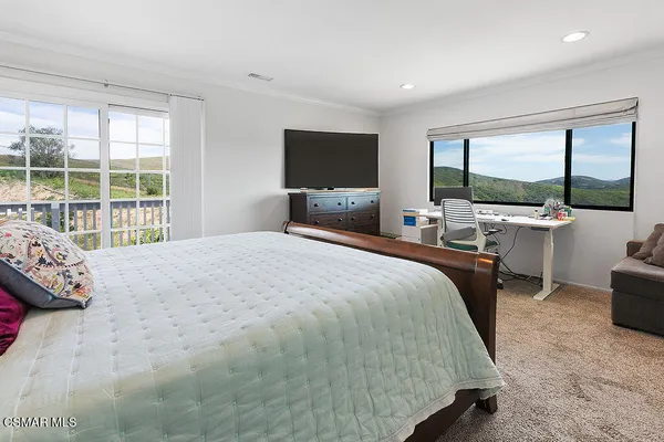 a bedroom with a large bed and a flat tv screen on dresser