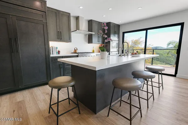 a kitchen with stainless steel appliances granite countertop a sink a stove a refrigerator with wooden floor and cabinets