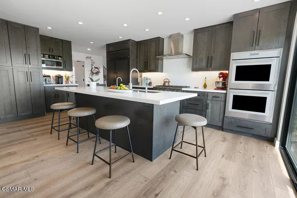 a kitchen with stainless steel appliances a stove a sink a microwave and a refrigerator