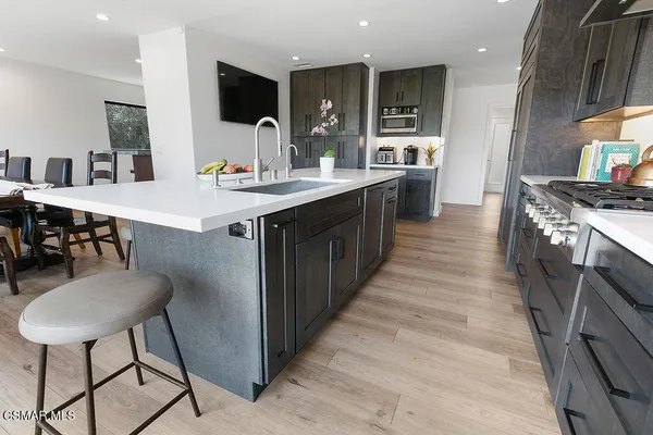 a large kitchen with stainless steel appliances a stove a sink dishwasher a dining table and chairs with wooden floor