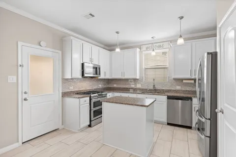 a kitchen with stainless steel appliances granite countertop a stove a sink and a refrigerator