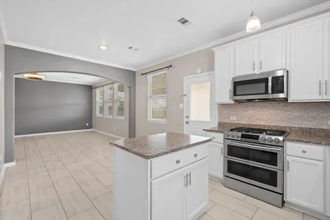 a kitchen with granite countertop a stove sink and microwave