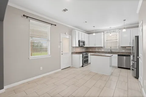 a kitchen with stainless steel appliances granite countertop a stove a sink dishwasher a refrigerator and white cabinets with wooden floor