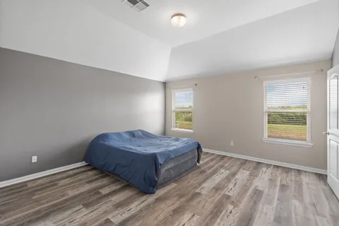 a spacious bedroom with a bed and wooden floor
