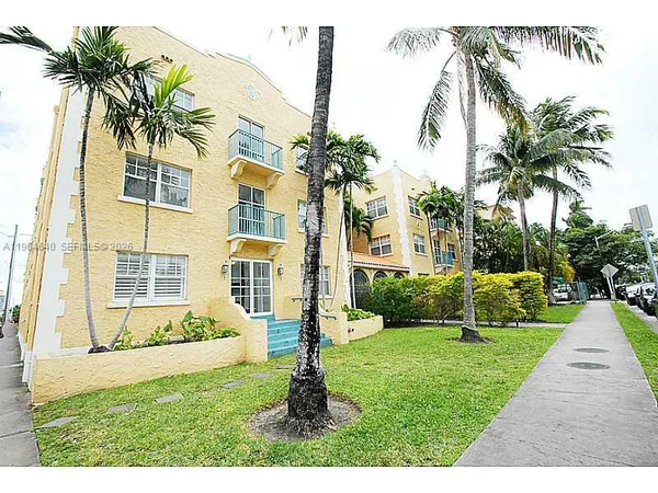 a front view of a house with a yard and palm trees
