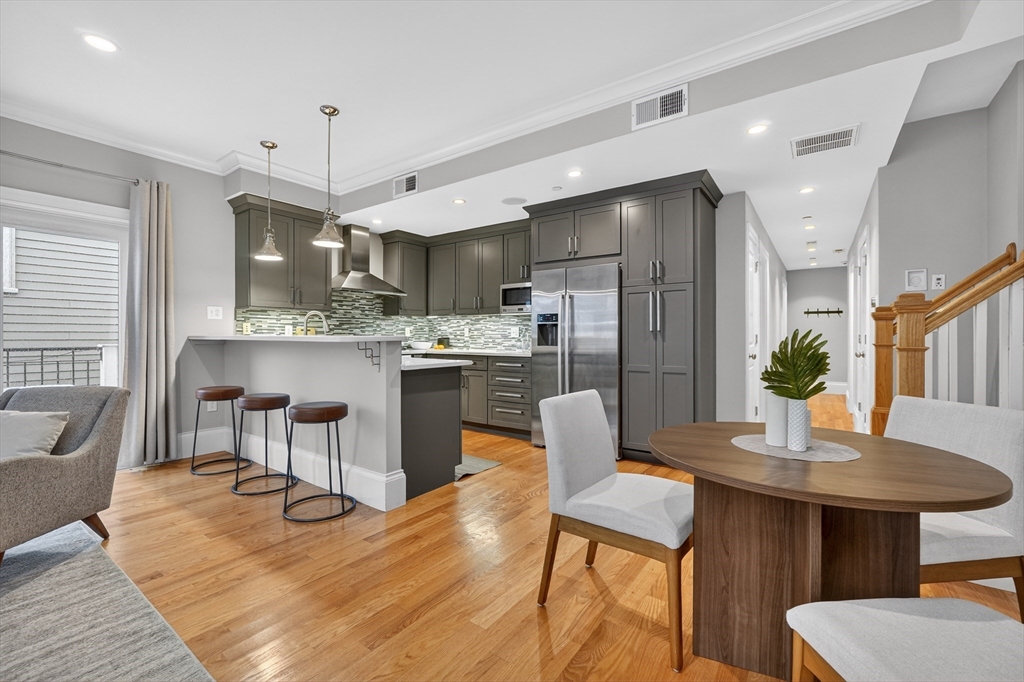 13 Howell Street, Unit 3 Boston, MA 02125 - Photo 7 of 31 a kitchen with stainless steel appliances kitchen island granite countertop a dining table chairs and a refrigerator