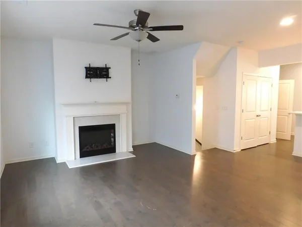 a view of an empty room with chandelier fan and fire place