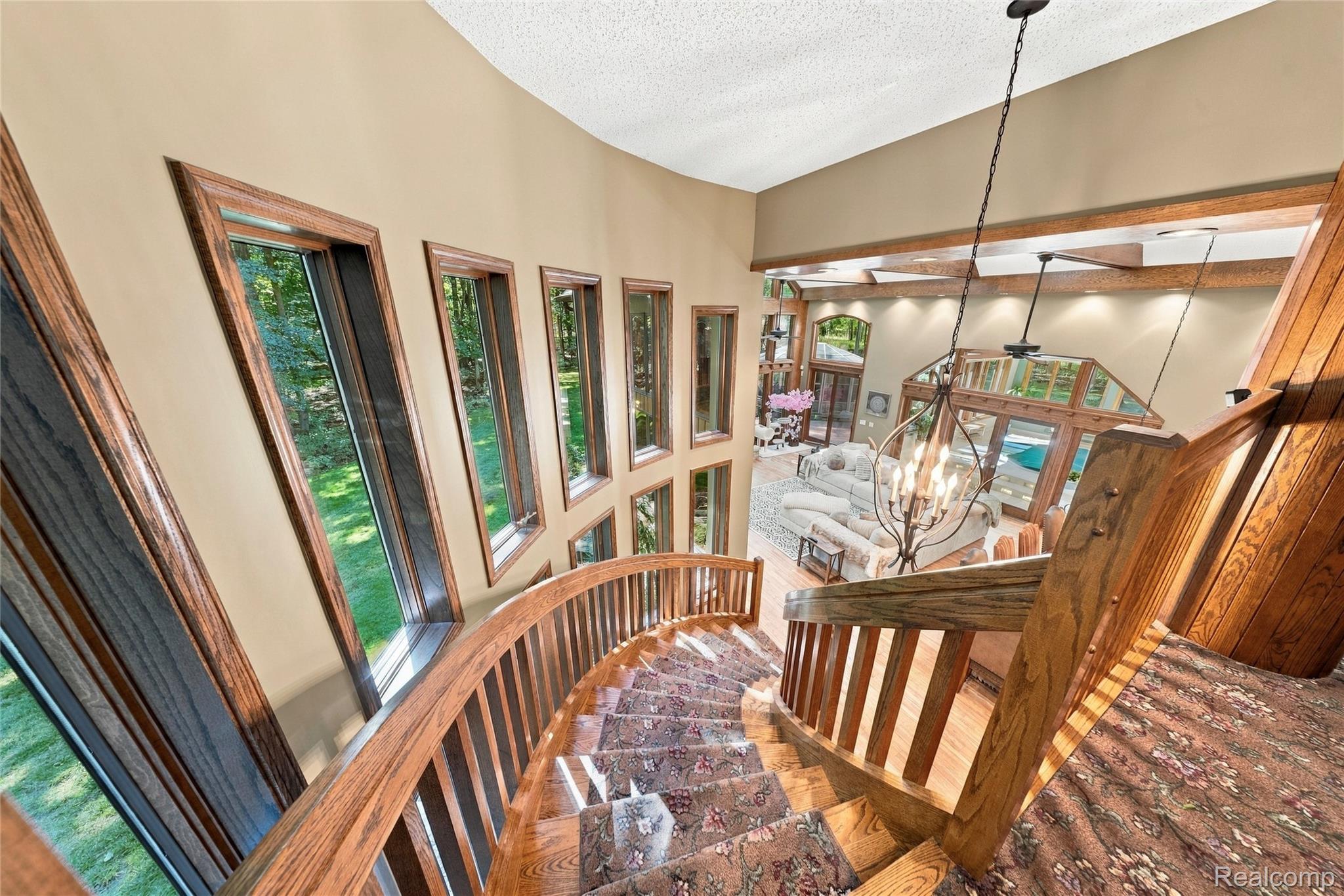 8931 Bridge Road Grosse Ile, MI 48138 - Photo 30 of 55 Curved wood staircase with patterned carpet and wood balusters