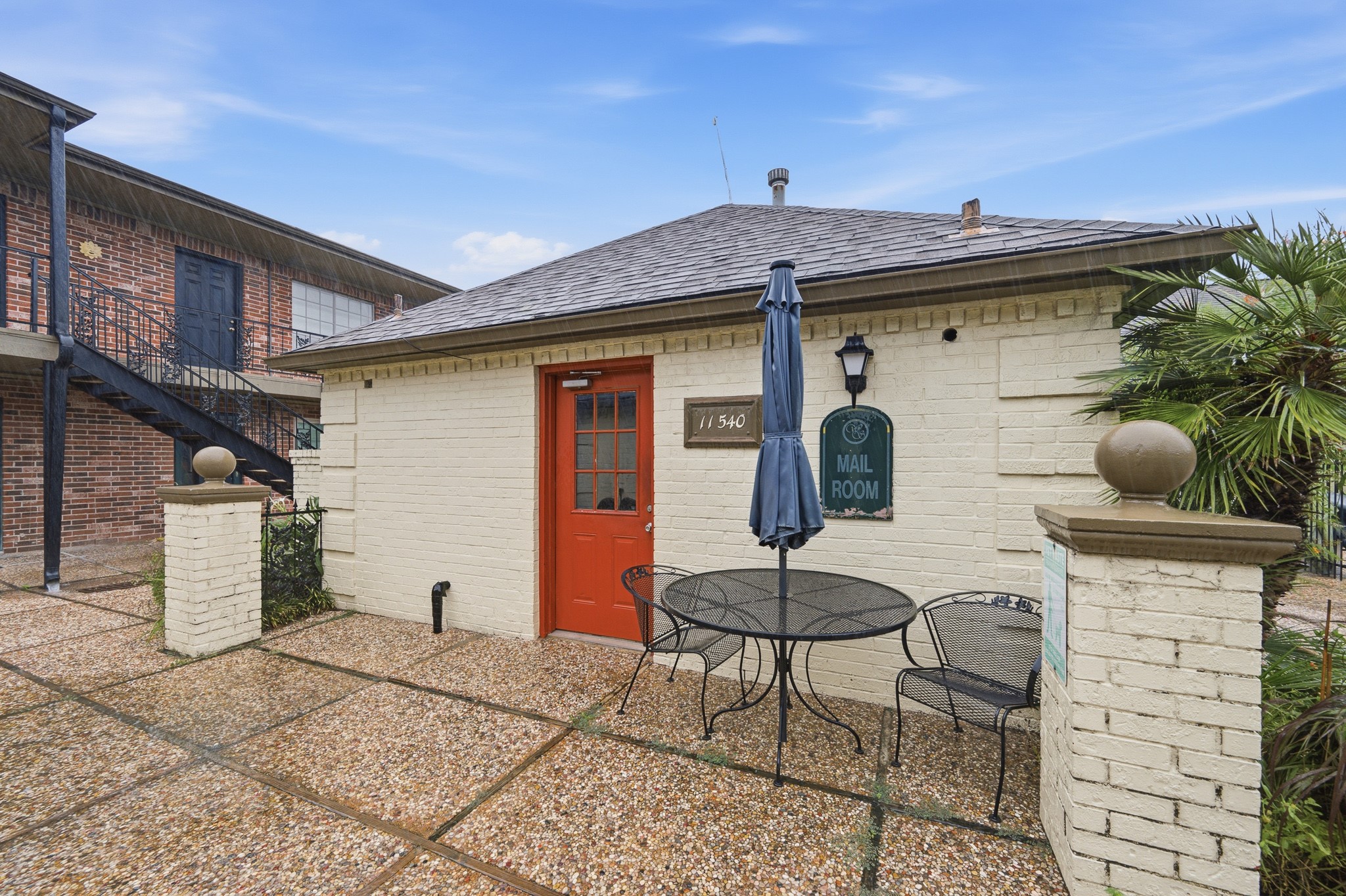 11550 Chimney Rock Road, Unit 133 Houston, TX 77035 - Photo 28 of 40 Charming mailroom building with a distinctive red door, cozy outdoor seating, and surrounded by classic brick architecture in a tranquil setting.