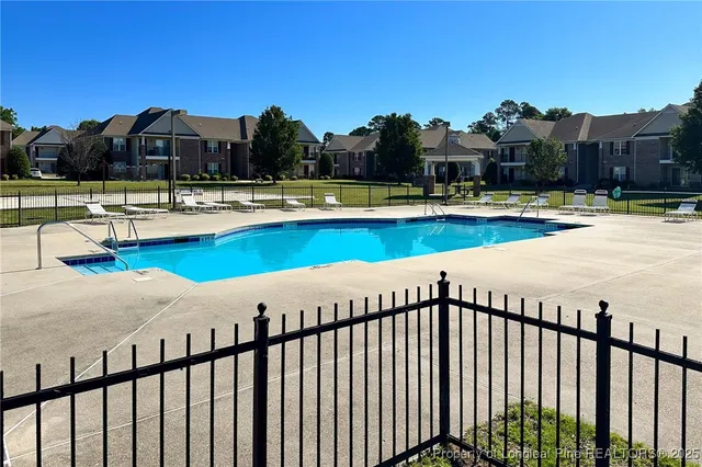 a view of a house with pool lawn chairs under an umbrella