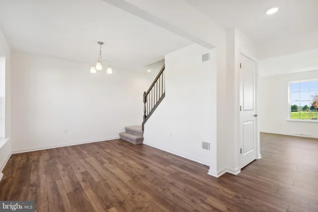 a view of an empty room with wooden floor and stairs