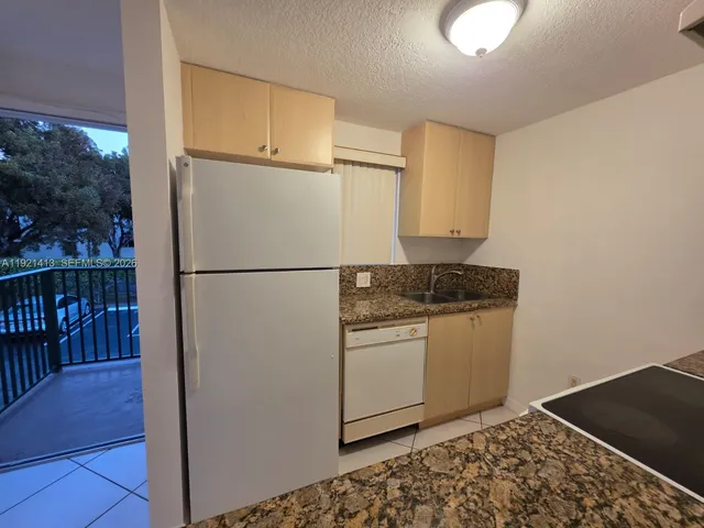 a kitchen with granite countertop white cabinets and refrigerator