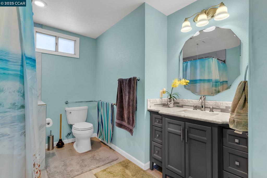 2113 Dalis Drive Concord, CA 94520 - Photo 16 of 22 a bathroom with a granite countertop toilet a sink and a mirror