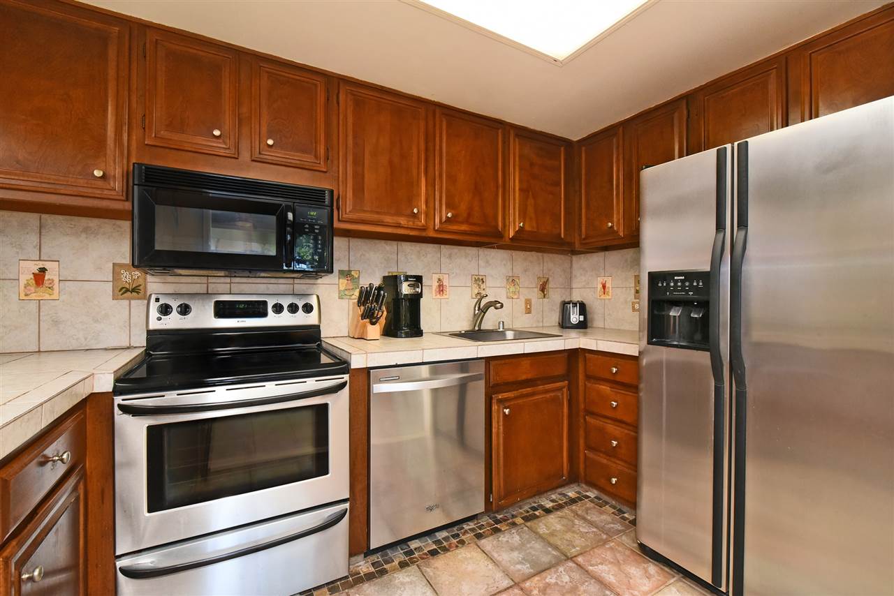 3875 Lower Honoapiilani Road, Unit B103 Lahaina, HI 96761 - Photo 17 of 30 a kitchen with cabinets stainless steel appliances and wooden cabinets