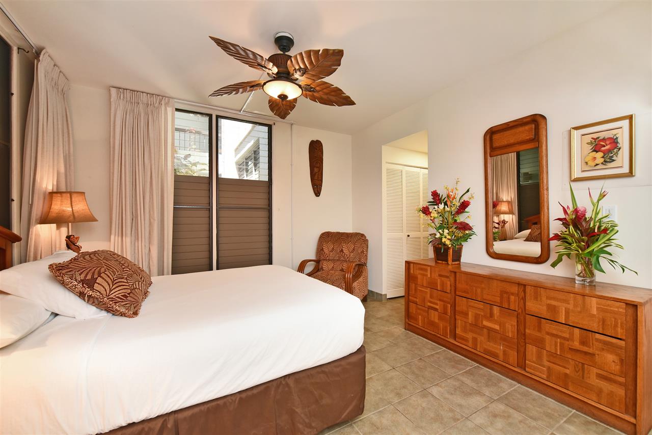 3875 Lower Honoapiilani Road, Unit B103 Lahaina, HI 96761 - Photo 21 of 30 a bedroom with a bed a chandelier and dresser