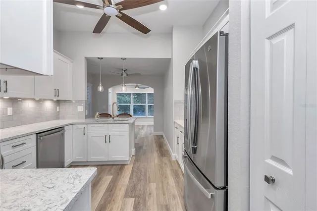a kitchen with granite countertop white cabinets and stainless steel appliances