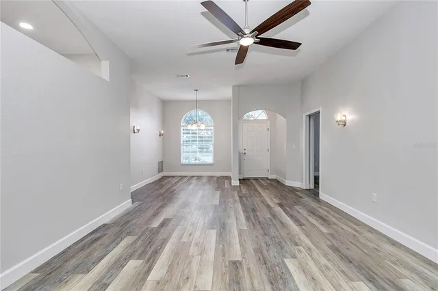 an empty room with wooden floor and a ceiling fan