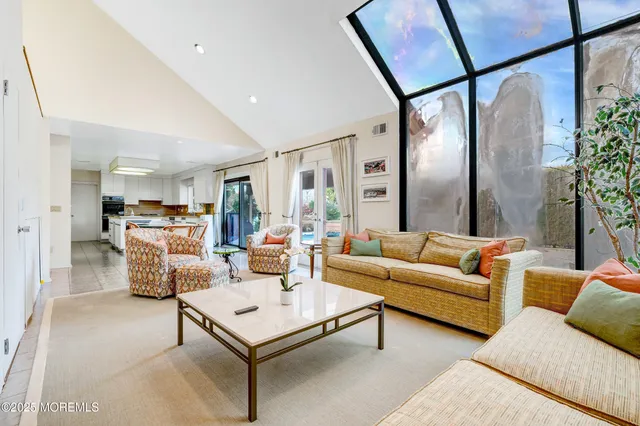 a living room with furniture and a large mirror next to a window