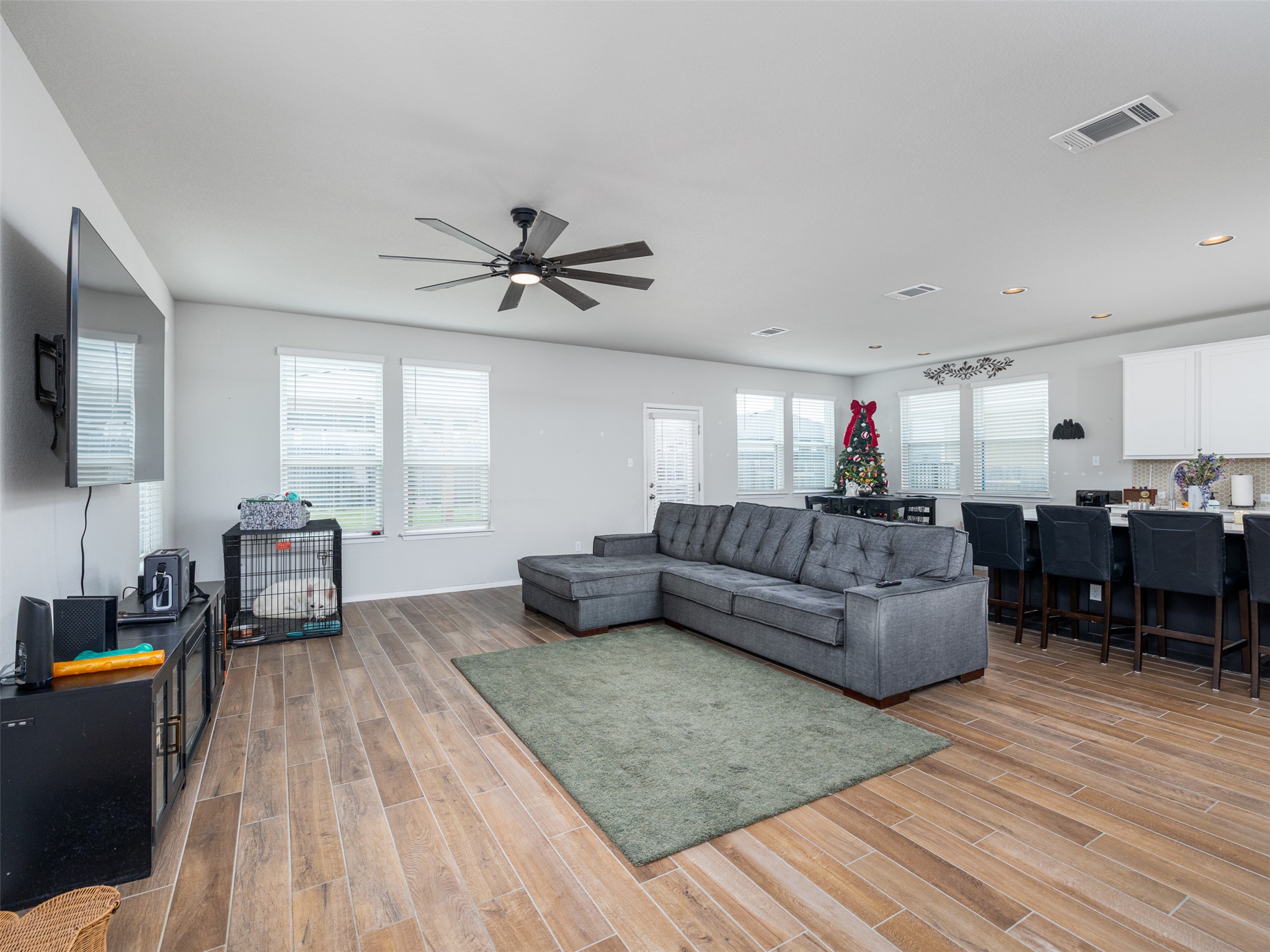 121 Graver Street Georgetown, TX 78626 - Photo 6 of 28 Hardwood floors stretch across this open-concept living space, leading to a modern kitchen bar with sleek seating.