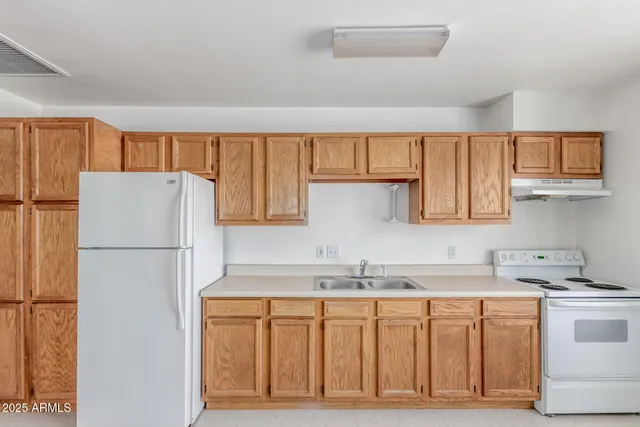 a kitchen with granite countertop a refrigerator a sink and white cabinets