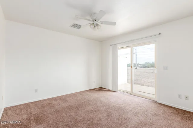an empty room with a ceiling fan and windows