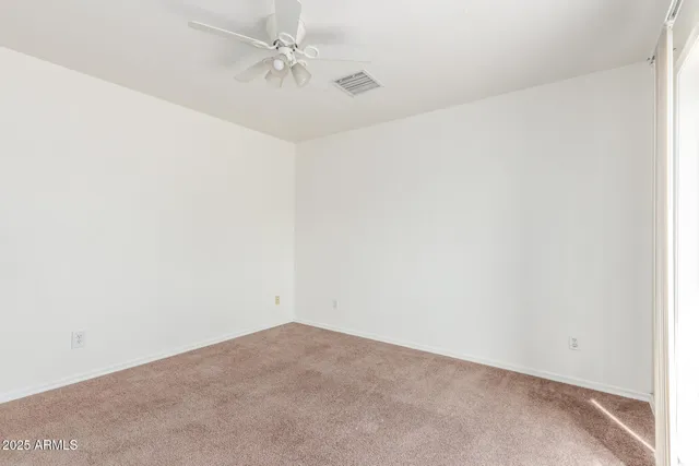 an empty room with a fan & a ceiling fan