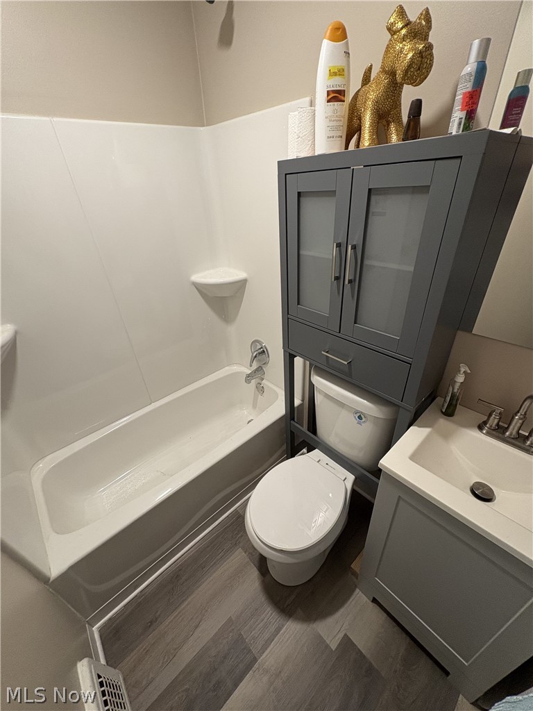 727 Wooster Road North Barberton, OH 44203 - Photo 32 of 37 Studio's Bathroom featuring a white bathtub, gray wood-finish vanity with an integrated sink, white toilet, gray over-toilet storage cabinet, and LVP flooring