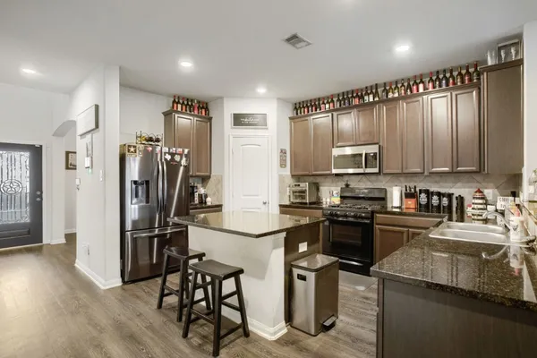 a kitchen with kitchen island granite countertop a refrigerator stove microwave and sink