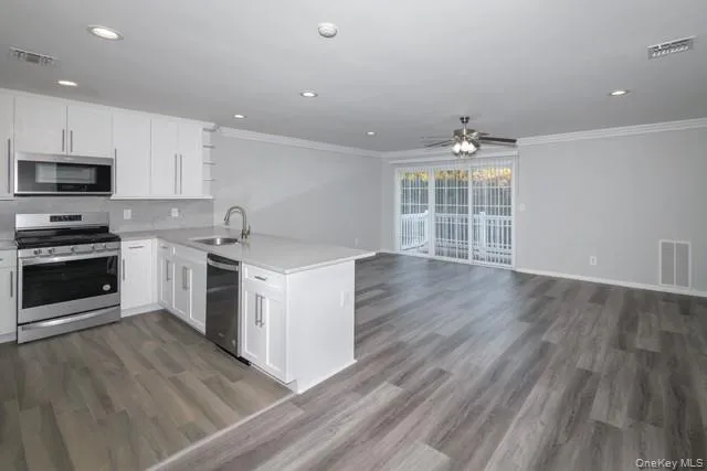 a kitchen with a sink wooden floor and stainless steel appliances