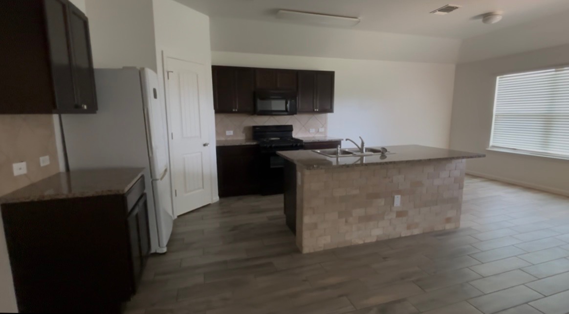 137 Rafe Court Kyle, TX 78640 - Photo 3 of 8 A contemporary kitchen space boasts an inviting island with a breakfast bar and modern appliances.