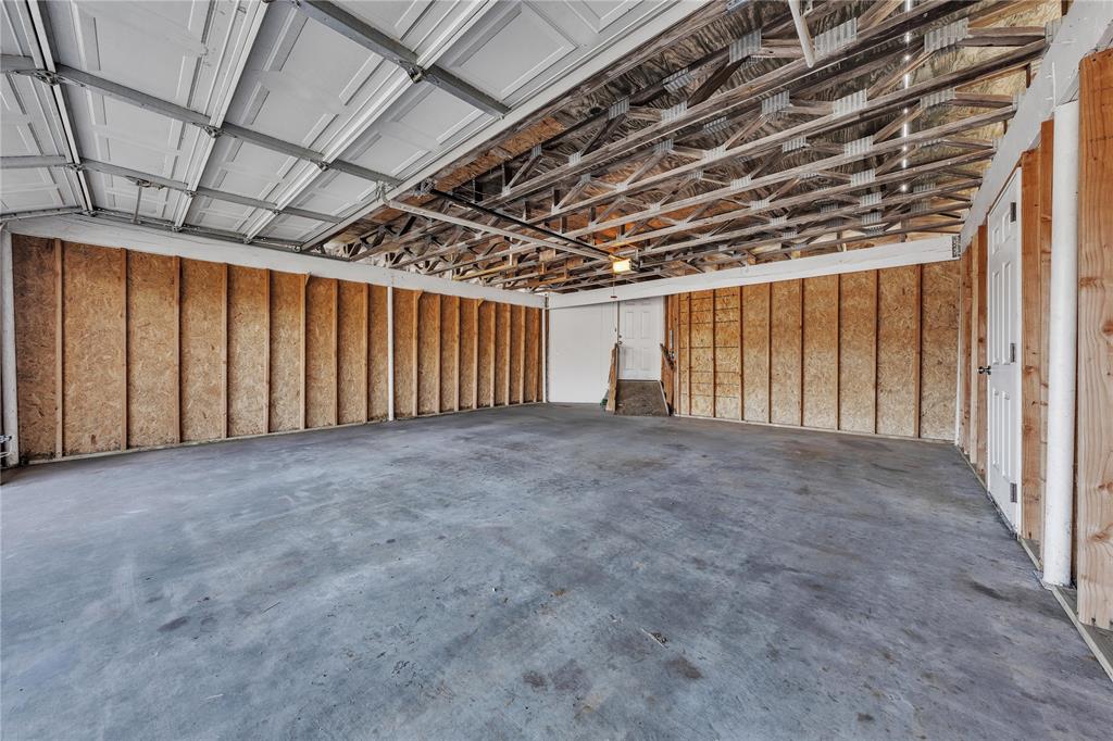 100 Rosedale Avenue Keene, TX 76059 - Photo 15 of 22 Spacious garage featuring a concrete floor, exposed wood framing, and an overhead garage door