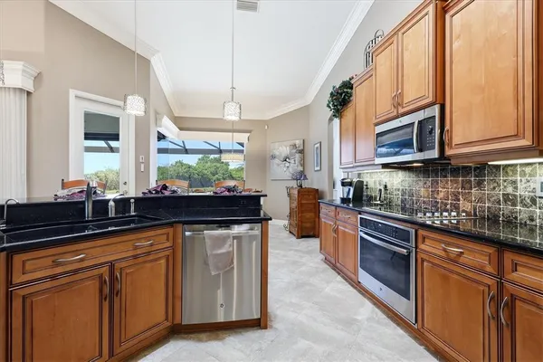 a kitchen with stainless steel appliances granite countertop a sink a stove and cabinets